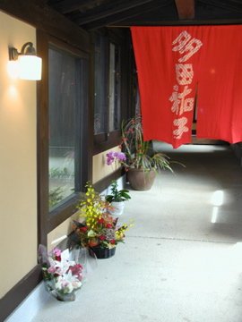 入口の手作り暖簾と贈られた花々の花回廊
